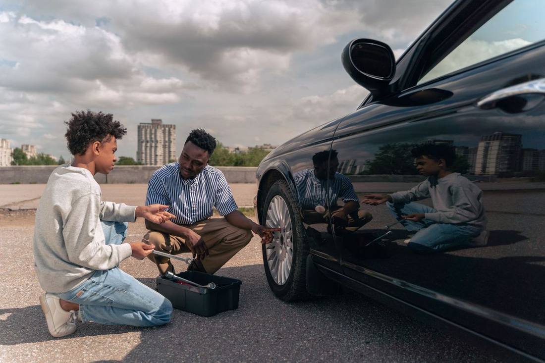 A senior chauffeur instructing a trainee on installing a child seat in an SUV at a fleet depot