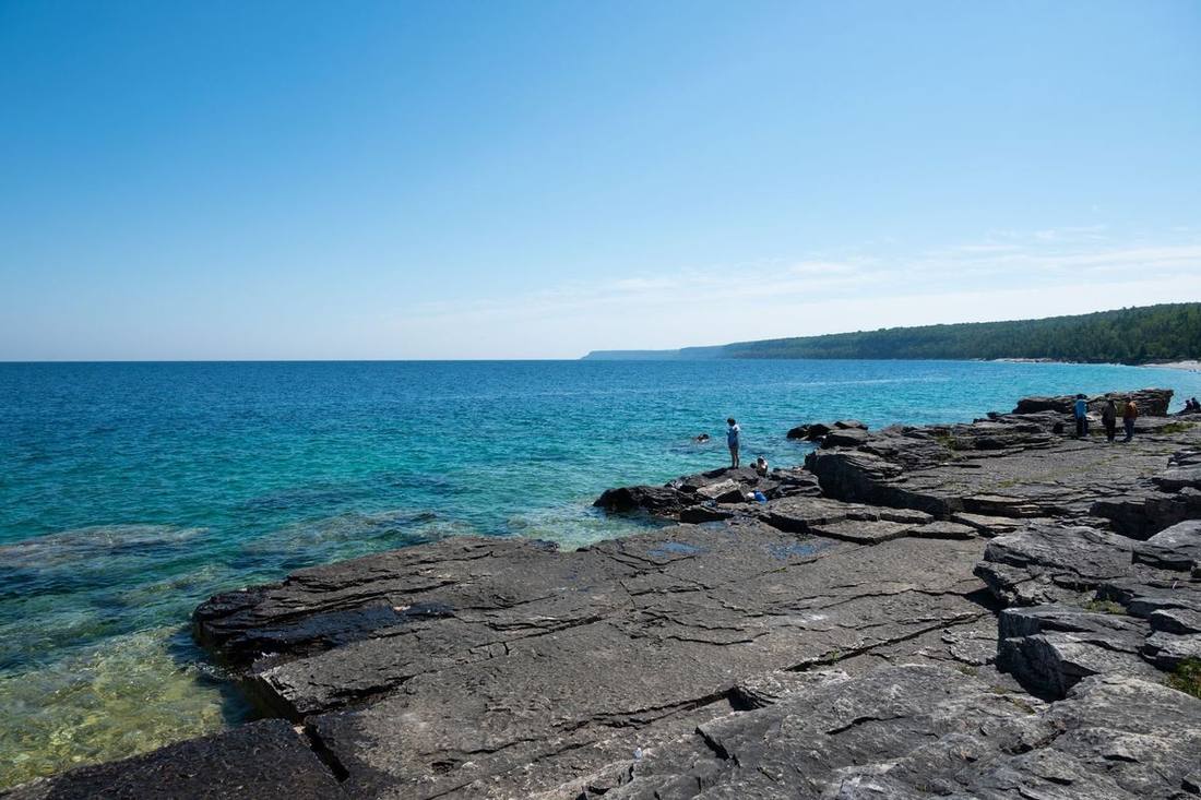 A black Sprinter at a Georgian Bay beach in summer with passengers unloading bicycles and bags