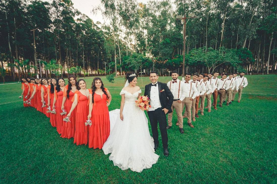 A bridal party beside a white stretch limousine and a black Sprinter van