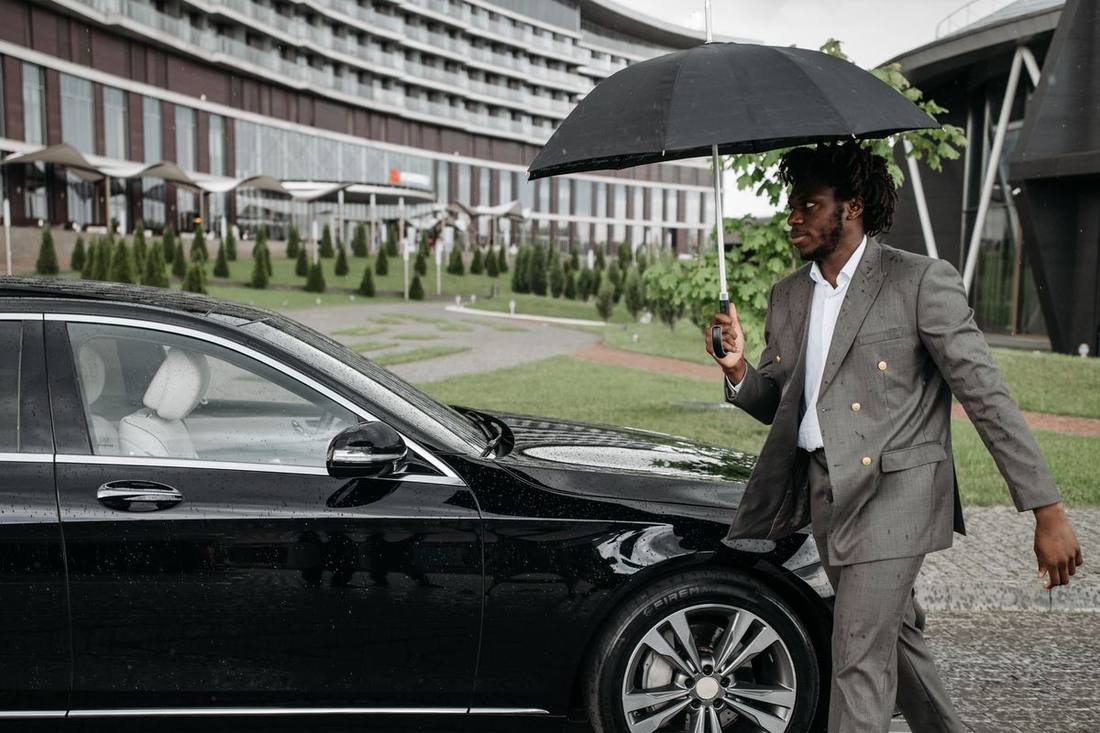 An executive stepping into a black sedan outside a suburban office campus