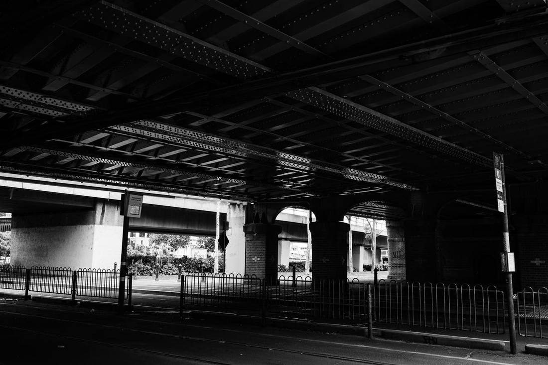 A black sedan on Lake Shore Boulevard beneath the elevated Gardiner Expressway with a closure sign on the ramp above