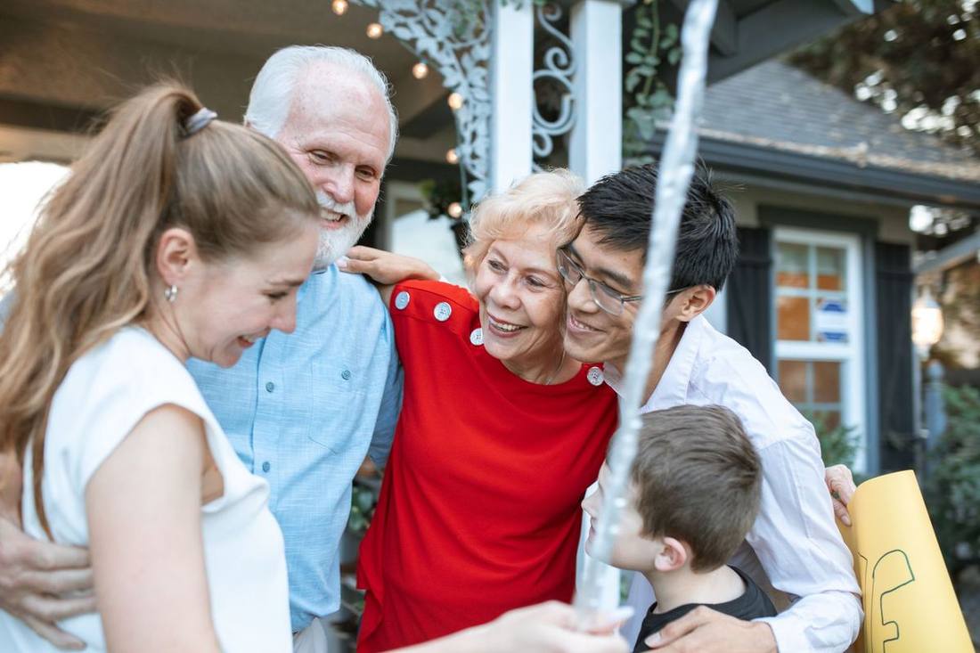 A family with grandparents boarding a Sprinter van outside a campus hall in June