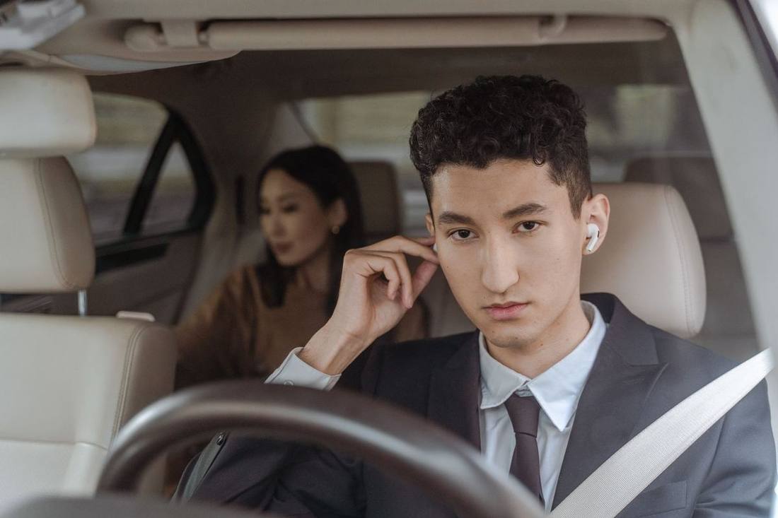 A senior chauffeur conducting a road test with an applicant at the wheel of a black sedan on a Toronto street