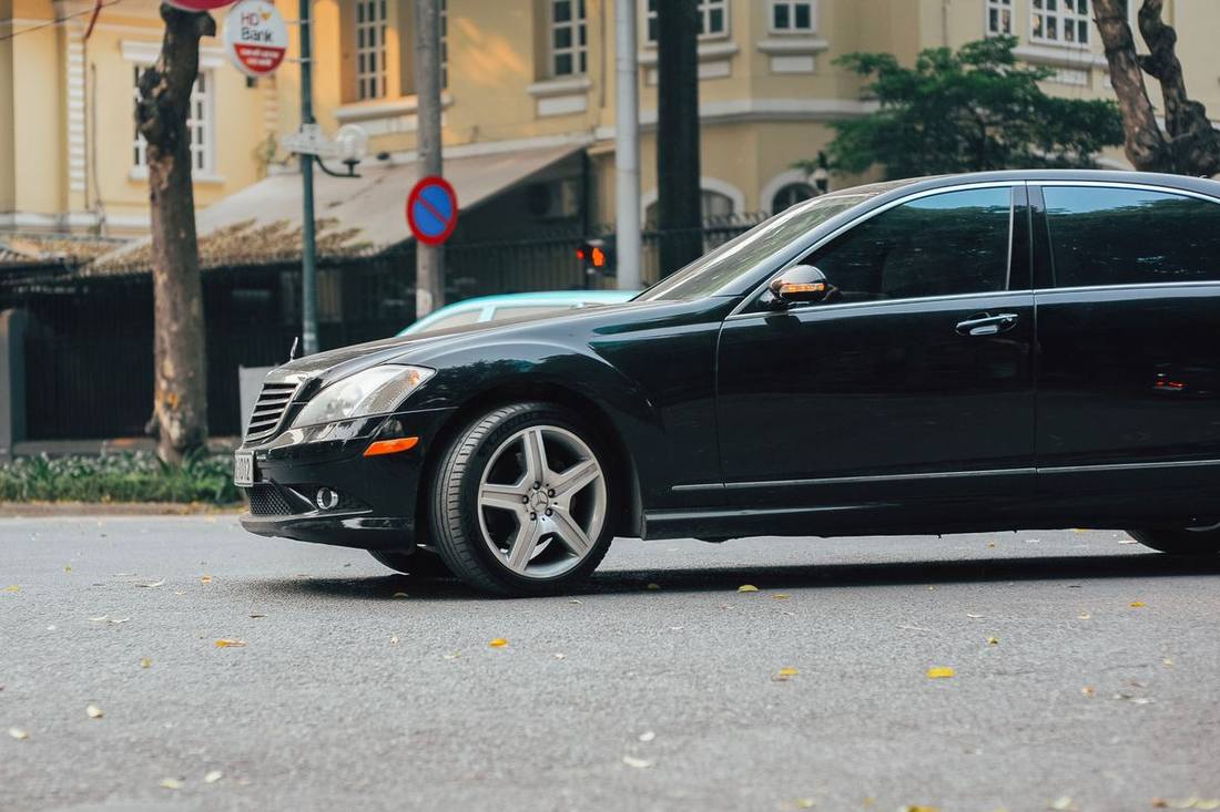 A black sedan waiting at a downtown corner at 3 a.m. with city lights behind