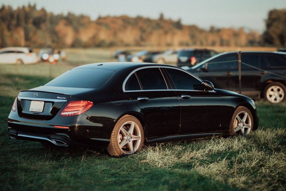 A black sedan with tinted rear windows and no branding waiting outside an office tower's side entrance