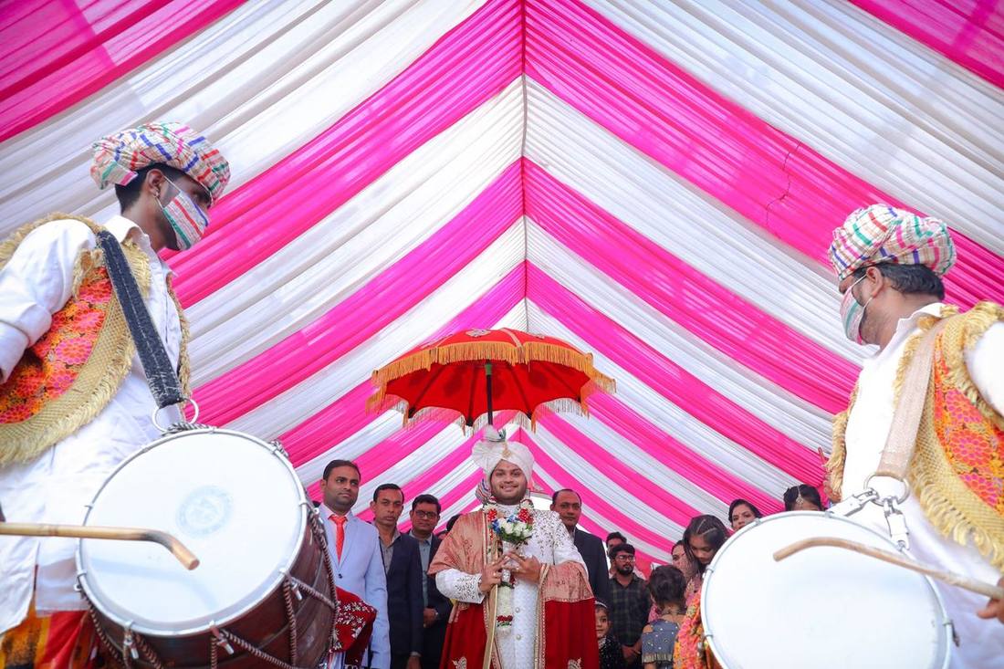 A baraat procession with a decorated stretch limousine and dhol players outside a Brampton banquet hall