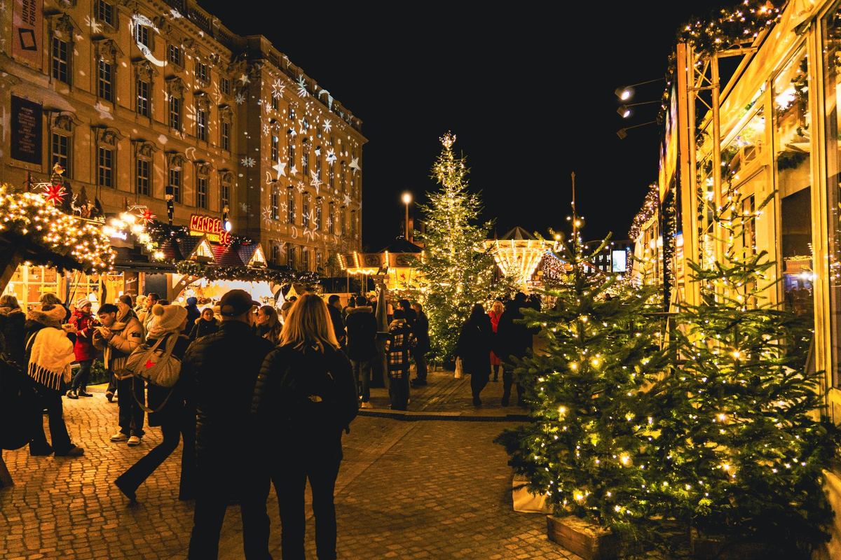 A family in winter coats stepping from a black SUV under holiday lights
