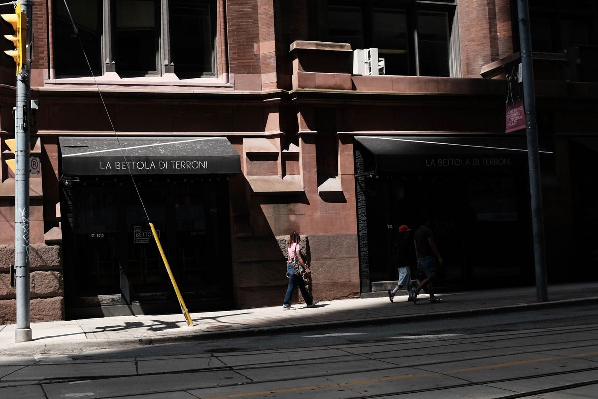 A couple leaving a restaurant on a quiet Toronto side street to a waiting black car