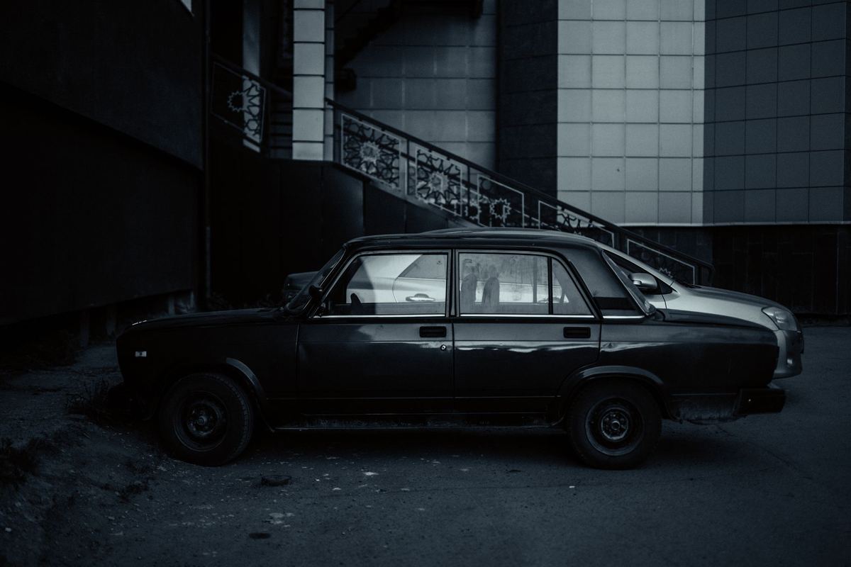A black sedan waiting on a side street outside a Toronto tasting-menu restaurant at night
