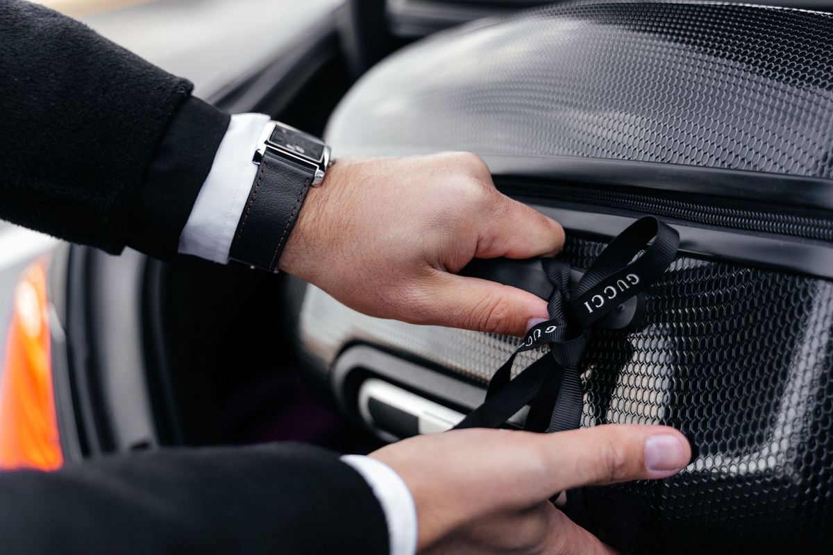 Luggage being handed from a black car's trunk to a hotel bell cart
