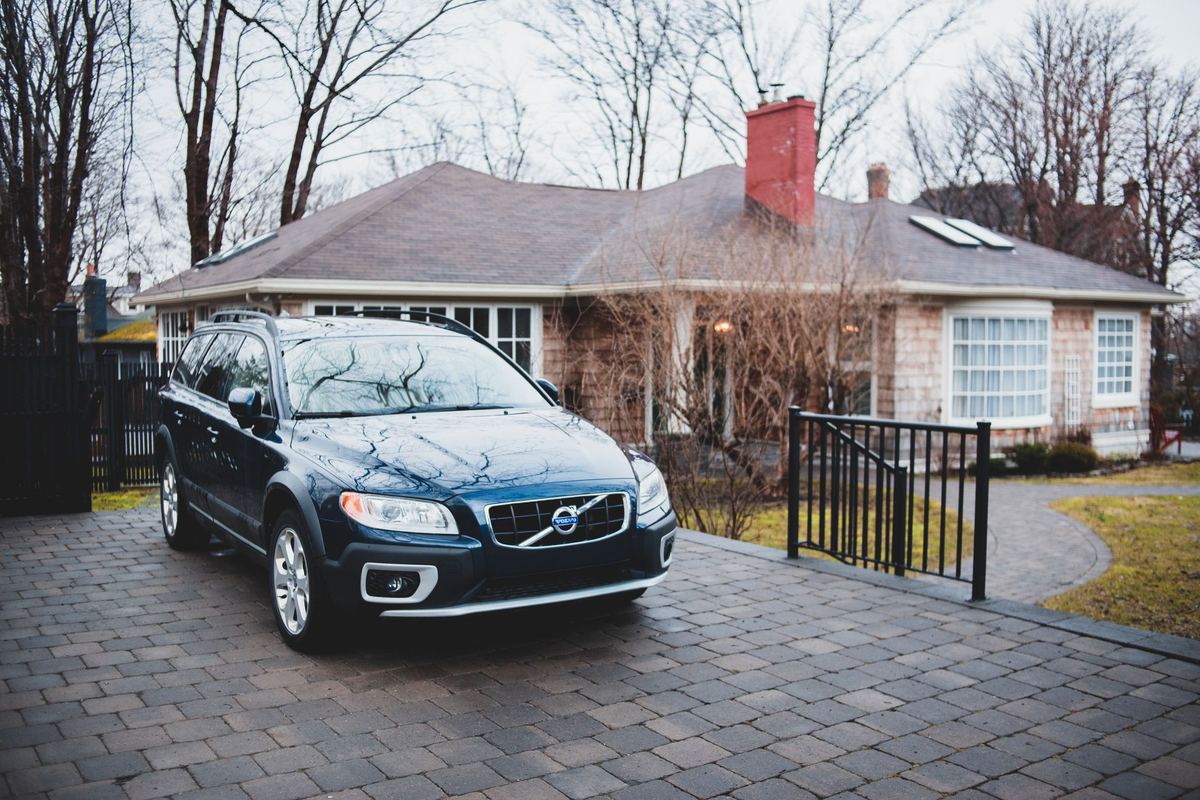 A black Escalade at a Lake Simcoe cottage's driveway with the lake and a dock beyond