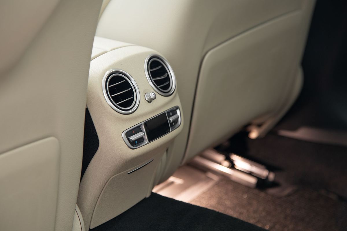 A detailer conditioning the rear leather seats of a luxury SUV with the door open
