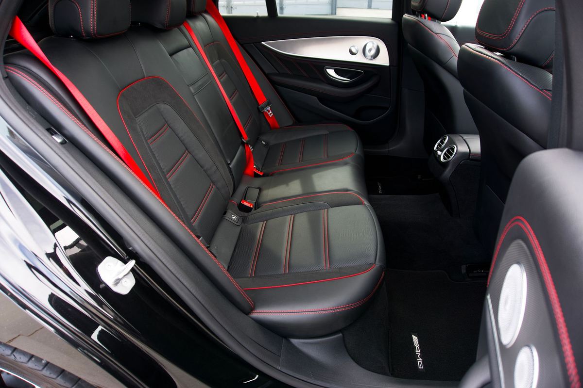 The rear seat of a black sedan prepared for a passenger with water, a charging cable and the sunshade drawn