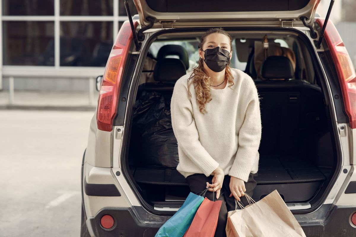 Shopping bags being loaded into a black car's trunk on a Yorkville side street