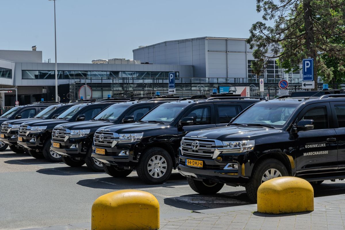 Black SUVs lined up at an airport pickup curb