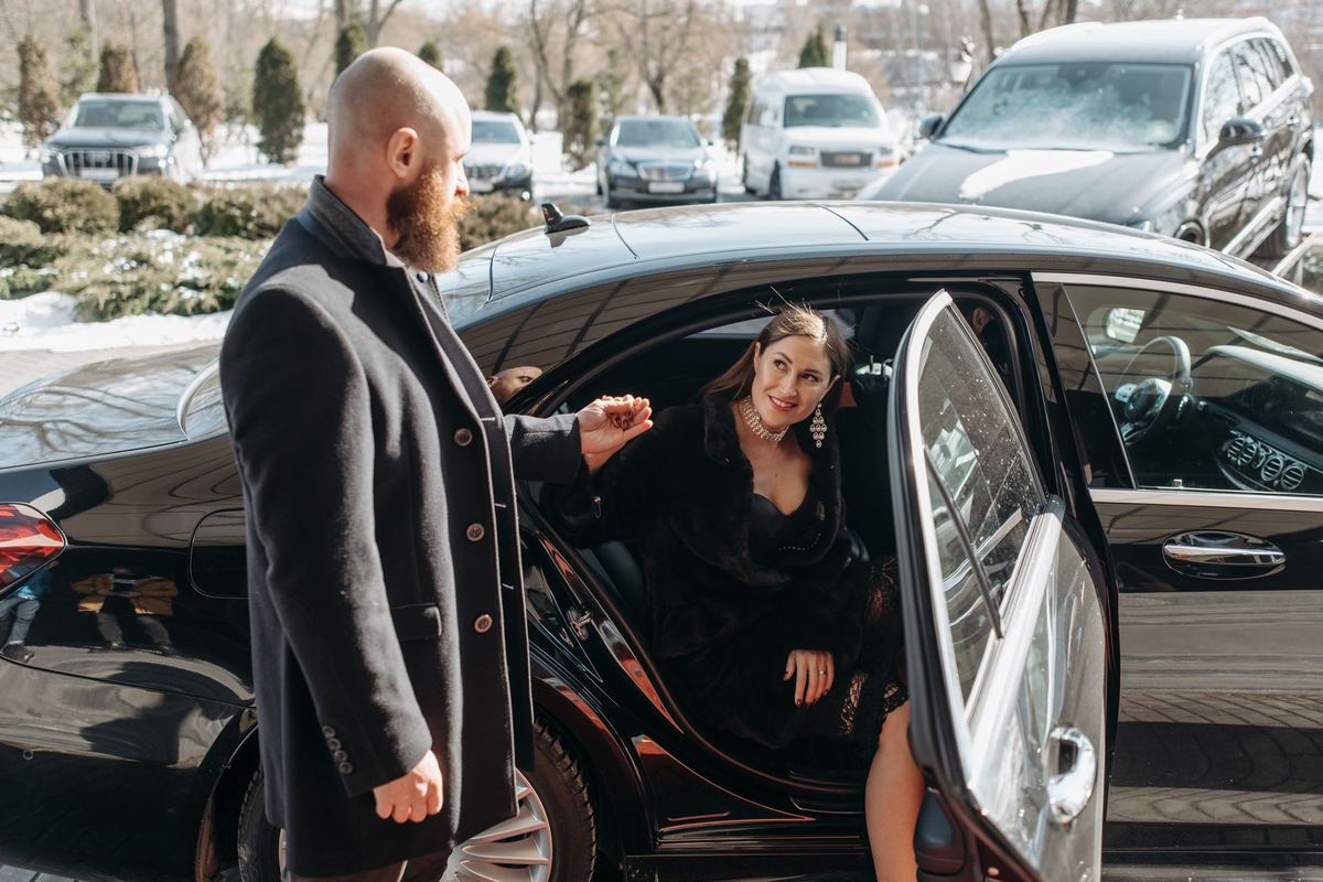 Stepping out of a black sedan at the door