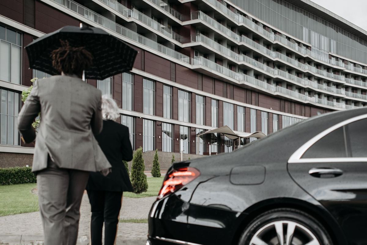 Executives walking to a waiting black sedan in the rain